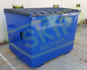 3m3 blue front lift bin with a black lid. Skip Factory logos showing on the wall behind.